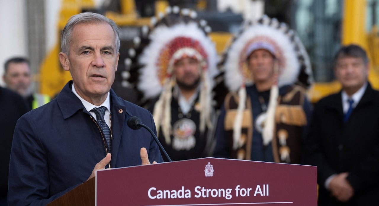 default-739 The Prime Minister speaks at a podium with two Indigenous leaders shown among a crowd in the background.